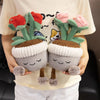 A hand holds a cute artificial flower plush doll with soft green leaves and pink flowers, featuring a brown seed pod base.