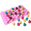 A pink silicone mold tray filled with small heart-shaped silicone molds in various colors like green, yellow, and purple.
