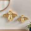 Golden bee-shaped resin wall decor mounted on a white wall.