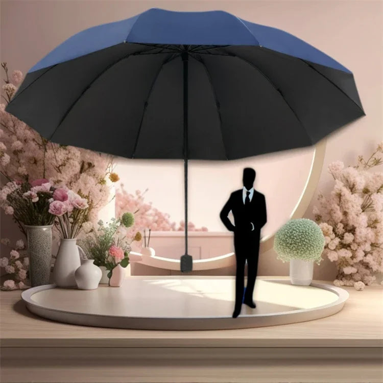 A black and blue oversized folding umbrella is displayed on a table next to pink flowers.