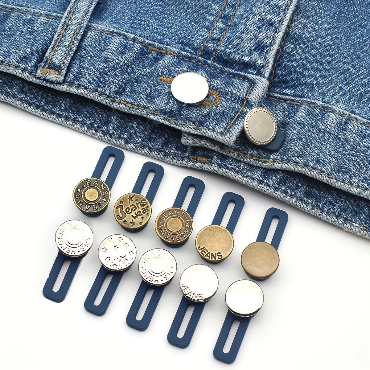 Six metal button waist extenders in various finishes are shown against a denim fabric background.