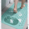 A person's feet are standing on a teal non-slip bath mat with massage nodes.