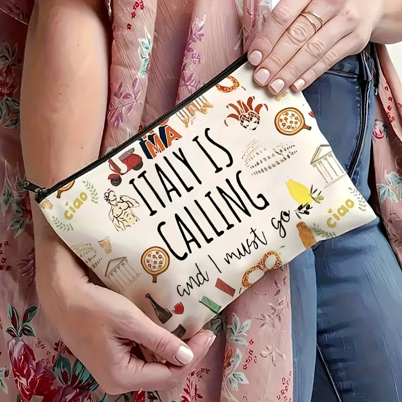 A beige makeup bag featuring an Italian theme with illustrations of landmarks and food, held by a person.