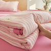 Pink and white striped breathable summer quilt rolled up on a pink surface.