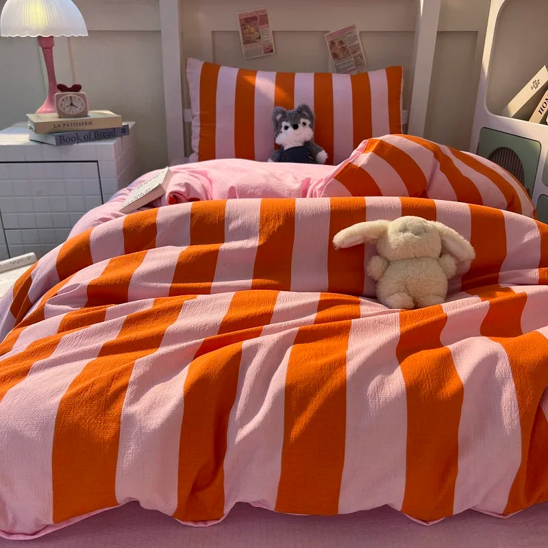 A bed decorated with an orange and pink striped duvet cover set featuring a stuffed animal pillow.