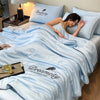A woman rests on a light blue comforter embroidered with the word Dreamcity and a feather design.