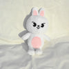 A white rabbit plush doll with pink accents sitting on a light background.