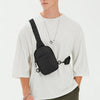 A male model wearing a white t-shirt and olive pants, holding a black 2-in-1 convertible sling bag.
