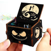 A dark wooden music box with a lid featuring a swirling silhouette and a skull design.