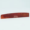 A wooden acoustic guitar bridge saddle with the text Guykor ATR-7632 engraved on it.