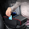A black car armrest cushion with cup holder and storage pockets is shown on a seat, with a hand holding a can above it.
