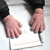 A pair of pink fluffy winter gloves resting on a lined piece of paper.