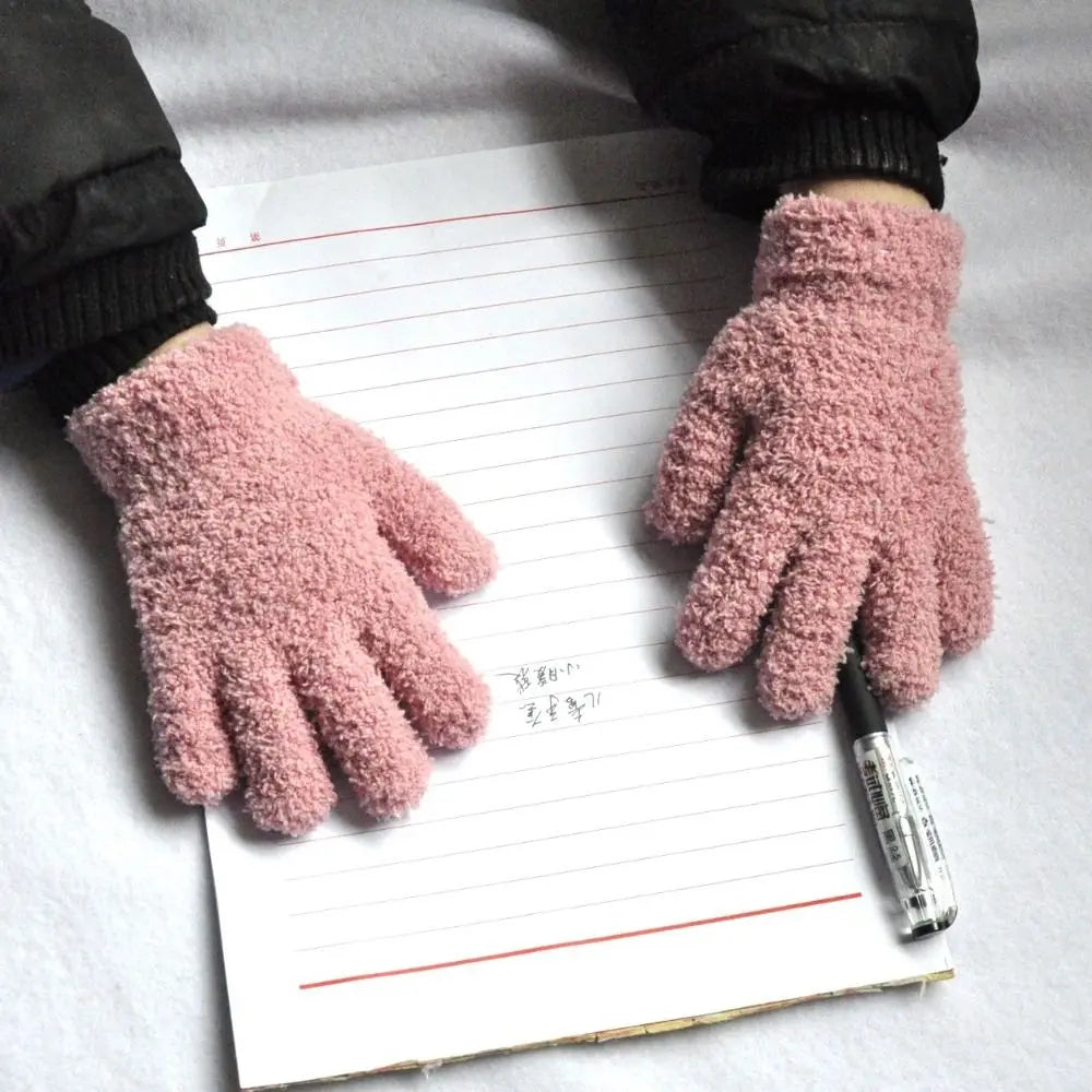 A pair of pink fluffy winter gloves resting on a lined piece of paper.