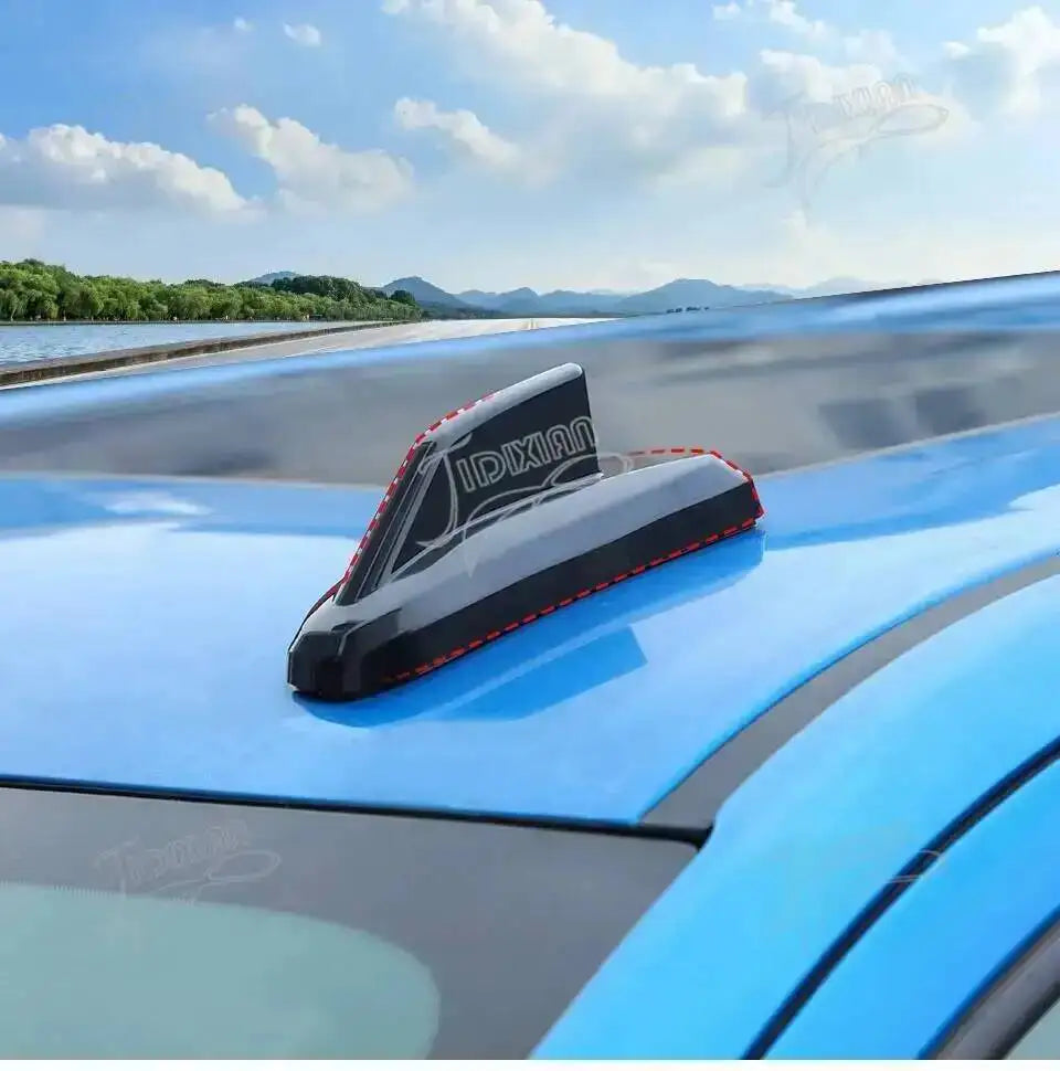 A close-up view of a black chrome-style antenna cover trim installed on the blue fender of a truck.