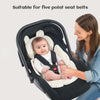 A woman is adjusting a baby in a black stroller seat cushion designed for five-point seat belts.