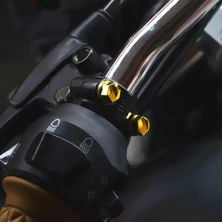 Close-up of a motorcycle screw cap cover set with decorative gold bolt caps on a black component.