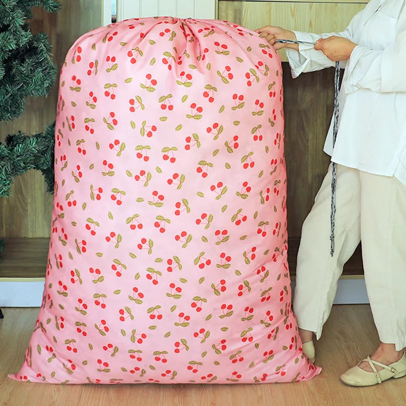 A pink drawstring laundry bag with a pattern of small red and green leaves is being held by a person.