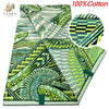 A close-up view of a green and white African wax print fabric featuring intricate patterns.