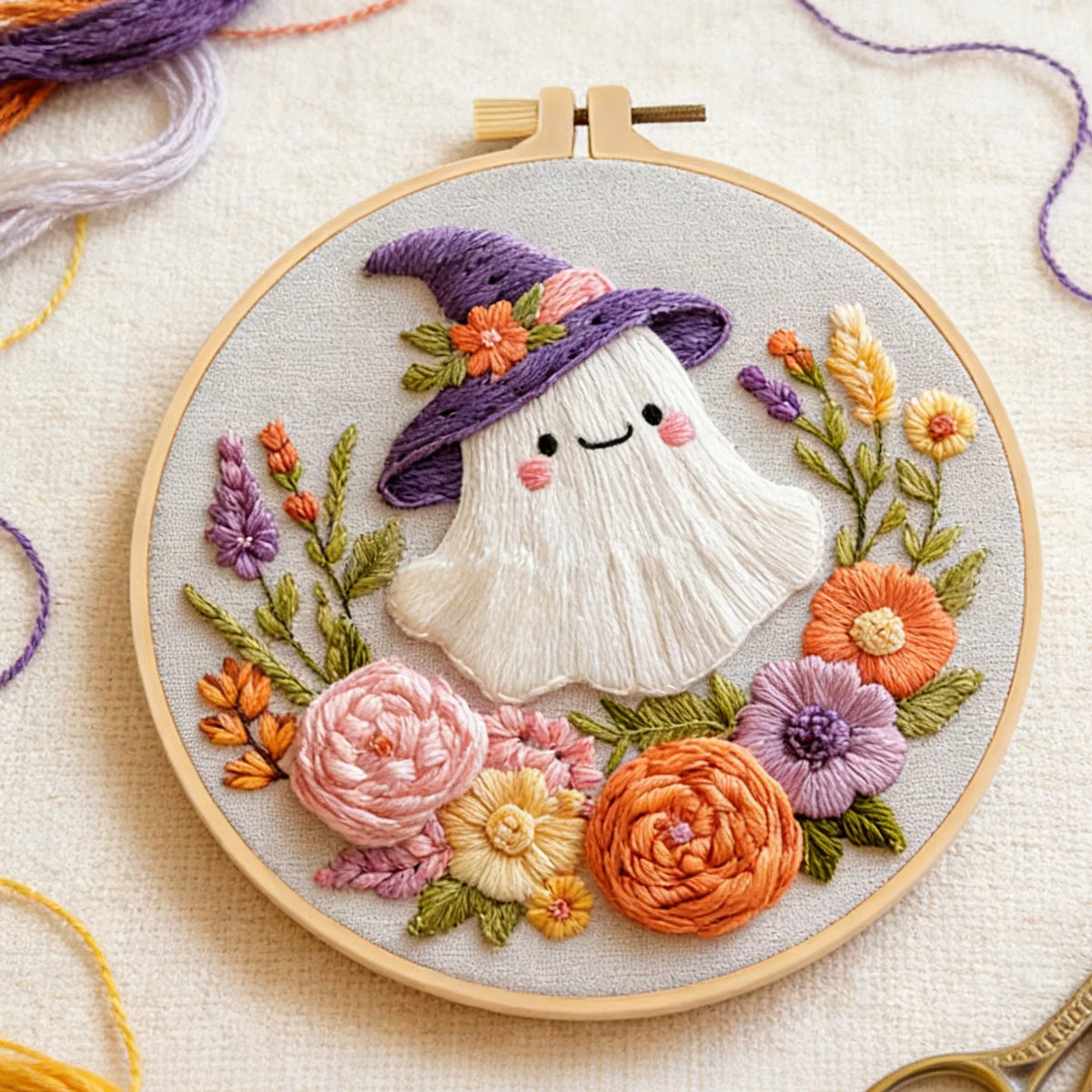 A cross stitch kit featuring a white ghost wearing a purple hat surrounded by colorful floral embroidery stitches.