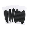 A pack of four black carbon fiber protective covers for car door handles.