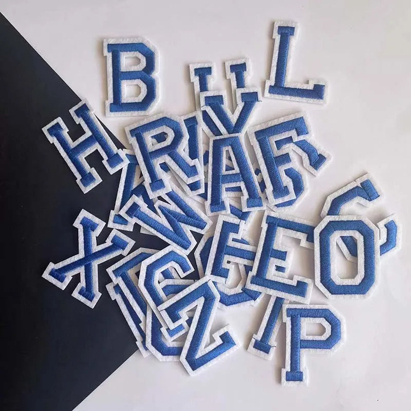 A collection of blue and white embroidered alphabet letters including B, L, H, R, V, X, W, Z, E, I, P, and O.