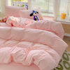 A pink cotton bedding set featuring a flat sheet, duvet cover, and pillowcases with a black and white character pillow.