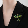 A close-up of an enamel dragon brooch with rhinestone accents pinned on a black blazer lapel.