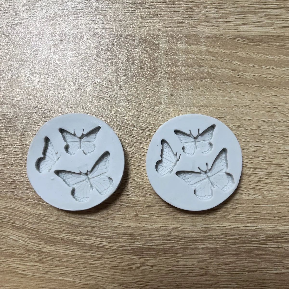 Two white silicone molds shaped like butterflies for crafting projects