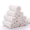 A stack of white soft natural cotton muslin baby washcloths rolled into cylindrical bundles.