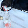 Eine klare Plastikflasche mit rolicher Flüssigkeit ist am Rückspiegel eines Autos befestigt.