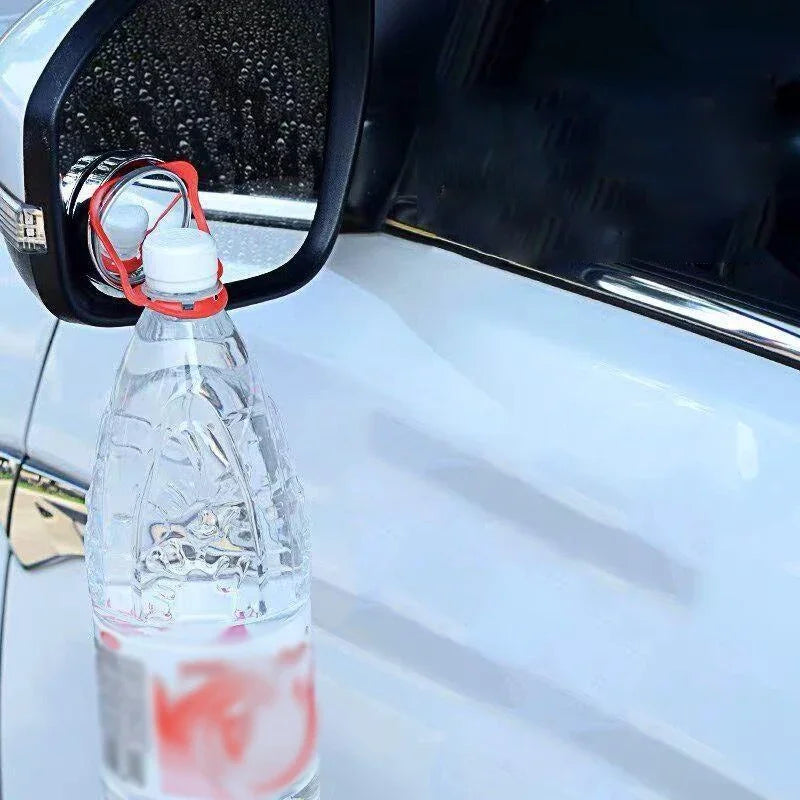 Eine klare Plastikflasche mit rolicher Flüssigkeit ist am Rückspiegel eines Autos befestigt.