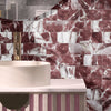 A close-up of a kitchen or bathroom wall tiled with reddish-pink marble self-adhesive 3D tiles.