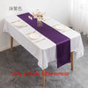 Elegant purple satin table runner displayed on a white tablecloth with pink floral accents.