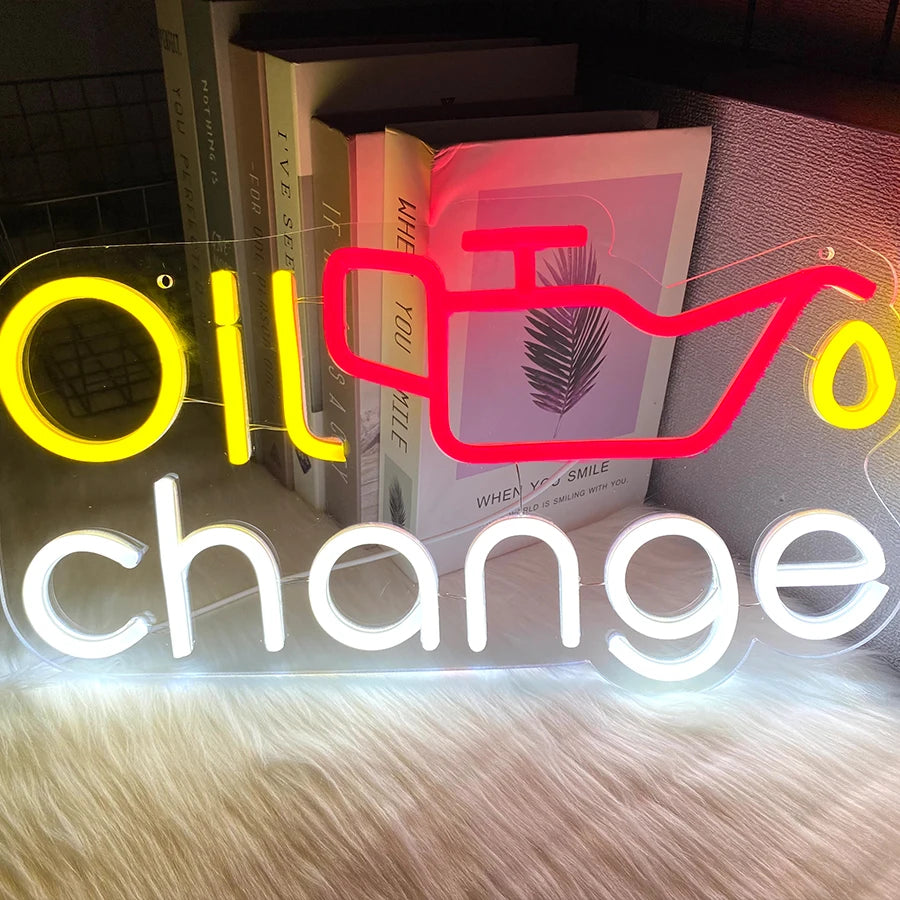 A neon sign spelling out Oil Change with a stylized silhouette of a palm frond.