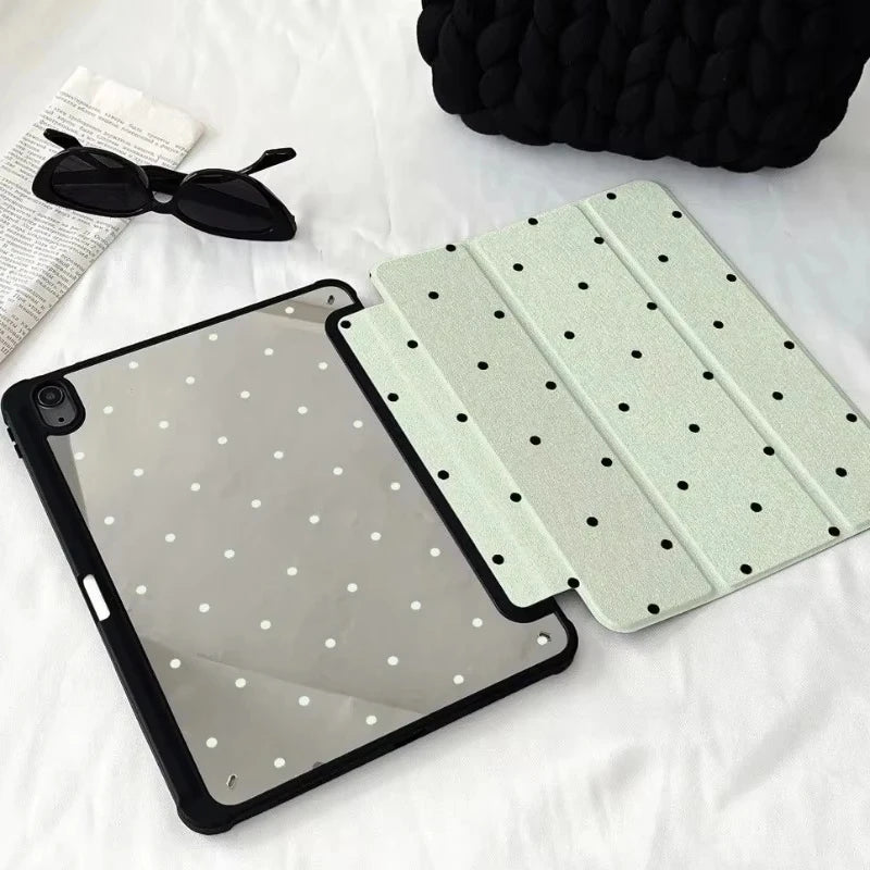 Schwarzes iPad mit hellgrüner Schutzhülle und Bleistiftfächern, neben Sonnenbrille und schwarzem Koffer