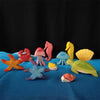 A collection of colorful Montessori playsilks shaped like sea creatures and mushrooms on a blue fabric.