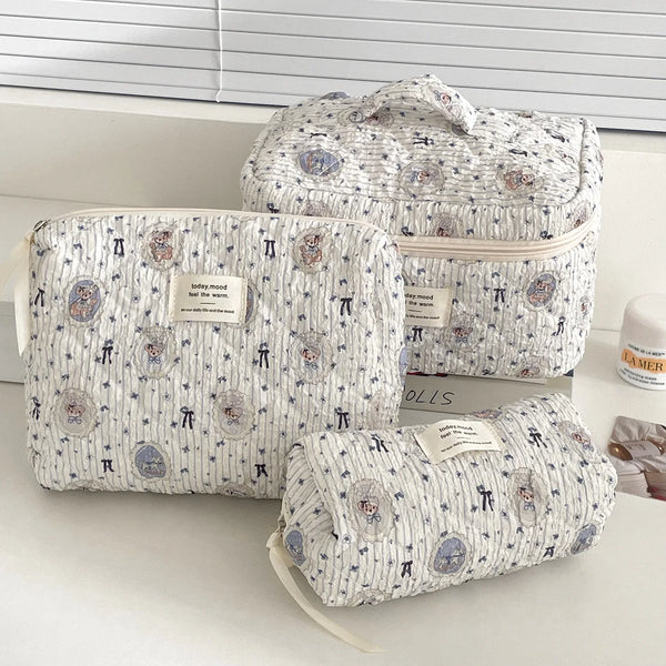 Colección de bolsos de maquillaje con forma de oso hechos de tela suave en patrones blancos y azules.