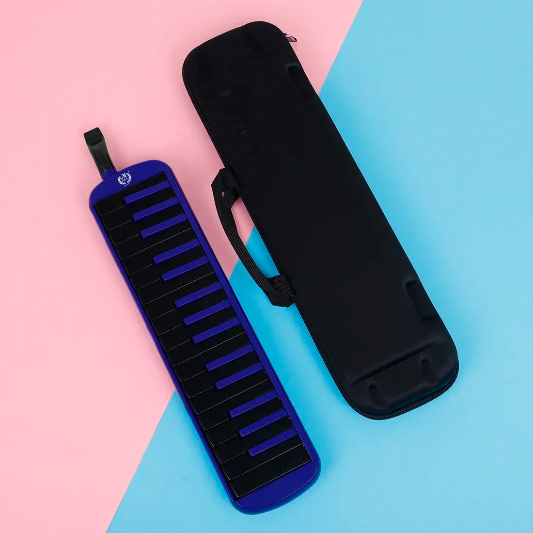A black 32-key melodica with a purple case and mouthpiece resting on a pink and blue background.