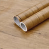 Two rolls of self-adhesive wood grain waterproof wallpaper lying on a wooden surface.