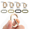 Eine Hand hält eine goldfarbene ovale Feder O-Ring-Schnalle, die ihre Größe und Form zeigt.
