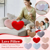 A set of heart-shaped plush pillows in pink, red, and blue colors displayed on a sofa.