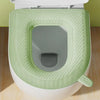 A white toilet seat with a light green textured cover and a matching seat cover.