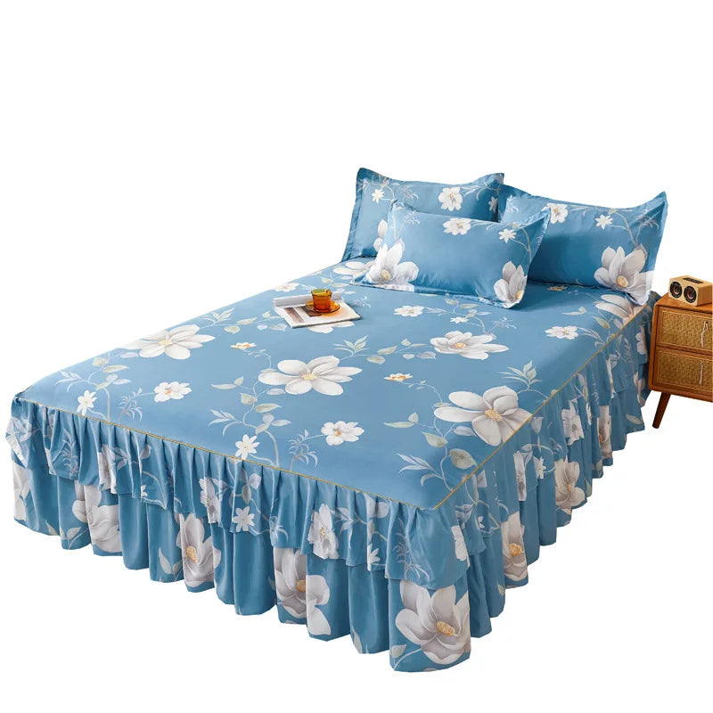 Jupe de lit à imprimé floral bleu clair avec volants et fleurs blanches sur un lit.