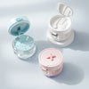 A portable denture case in light blue and white, showing an open lid and a separate pink storage container with a cleaning br