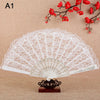 White lace folding fan with floral design displayed against a background of red blossoms.