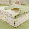 A stack of light green and cream floral quilted linens with a small stuffed rabbit on a pale green background.