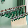 A set of five anti-slip stainless steel hangers with clips for pants and skirts, featuring a green finish.