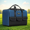 A dark blue heavy duty tool bag with black accents and multiple pockets resting on green grass.