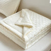 A stack of white breathable waffle-weave summer quilts folded neatly on a bed.