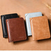Three slim PU leather card holder wallets in black, light blue, and tan resting on a brown surface.